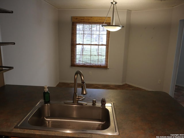 kitchen featuring a textured ceiling, decorative light fixtures, ornamental molding, and sink