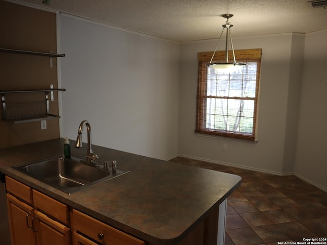 kitchen featuring a textured ceiling, dishwasher, sink, and hanging light fixtures