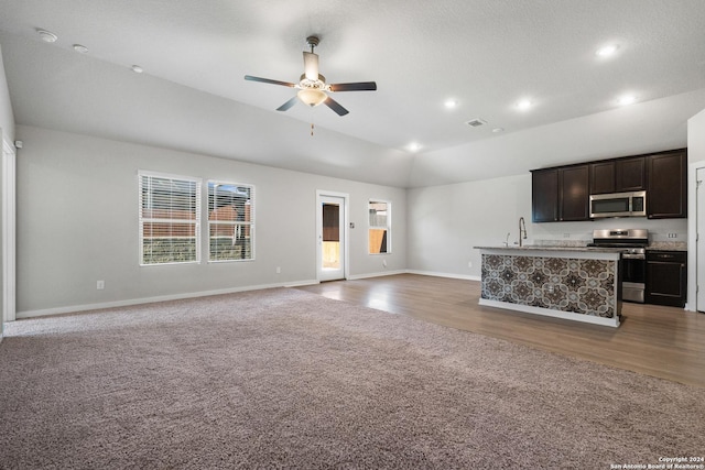 unfurnished living room with a textured ceiling, vaulted ceiling, ceiling fan, sink, and hardwood / wood-style flooring