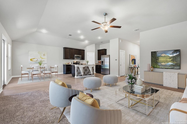 living room featuring ceiling fan, light hardwood / wood-style flooring, and lofted ceiling