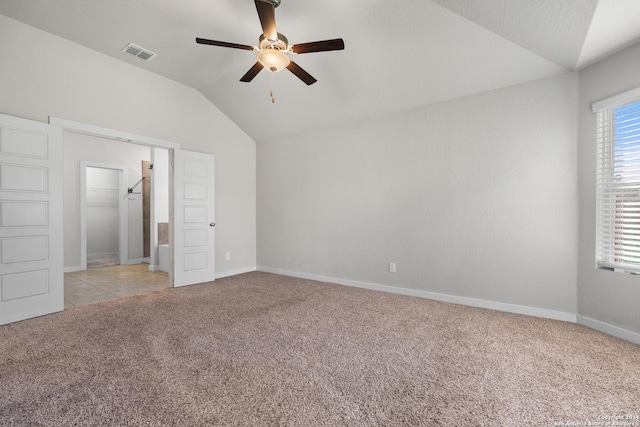 unfurnished bedroom with ceiling fan, light colored carpet, vaulted ceiling, a walk in closet, and a closet