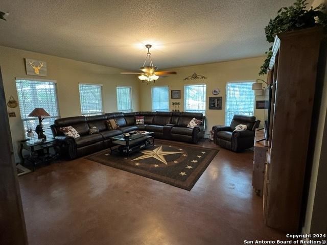 living room featuring ceiling fan and a textured ceiling