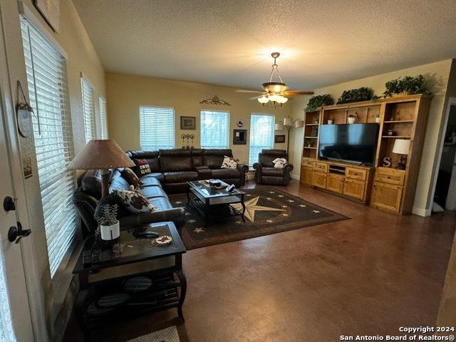 living room with ceiling fan and a textured ceiling