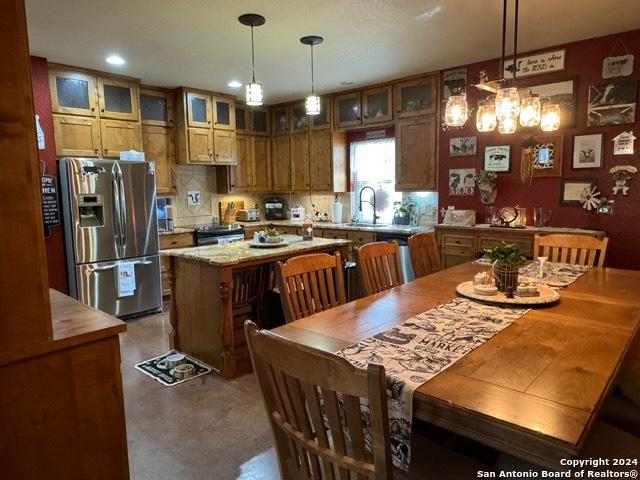 kitchen with decorative light fixtures, a kitchen island, concrete flooring, and appliances with stainless steel finishes