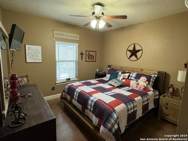 bedroom with ceiling fan and a textured ceiling