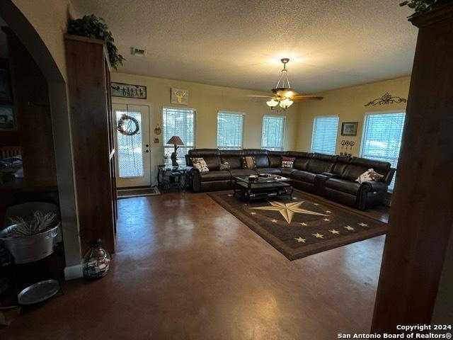 living room featuring ceiling fan and a textured ceiling