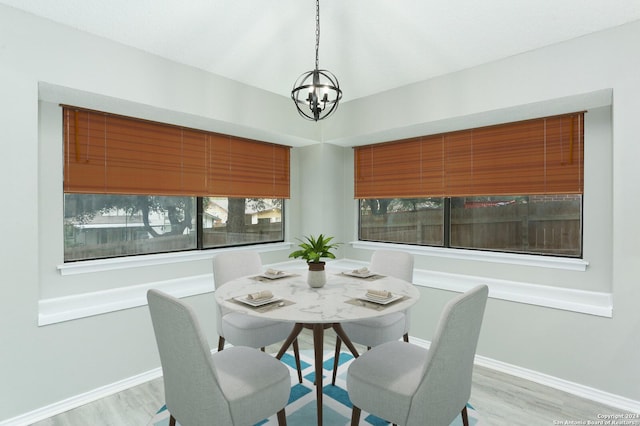 dining room with a healthy amount of sunlight, light hardwood / wood-style floors, and an inviting chandelier