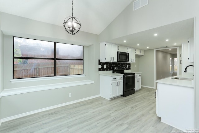 kitchen with electric range, pendant lighting, white cabinets, and sink