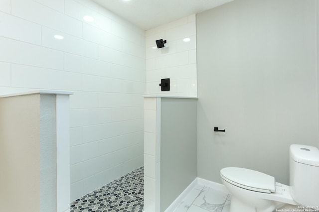 bathroom featuring toilet and a tile shower