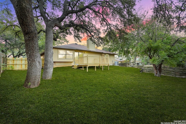 yard at dusk featuring a deck