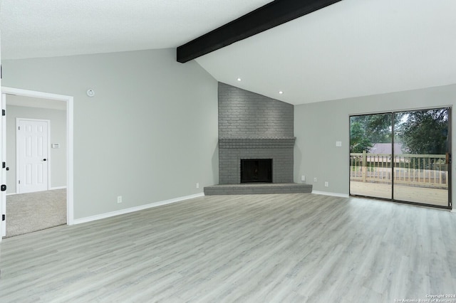 unfurnished living room featuring a fireplace, lofted ceiling with beams, and light wood-type flooring