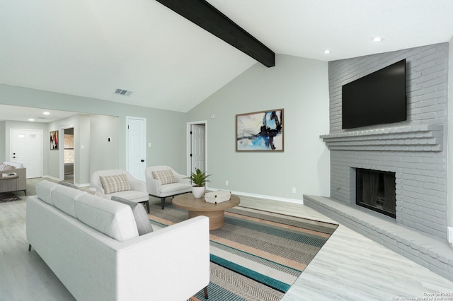 living room with vaulted ceiling with beams, a fireplace, and light wood-type flooring