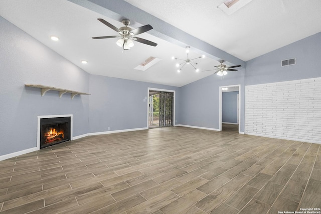 unfurnished living room with ceiling fan with notable chandelier, wood-type flooring, and vaulted ceiling