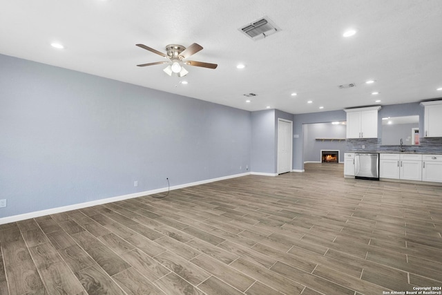 unfurnished living room with ceiling fan, light hardwood / wood-style flooring, and sink