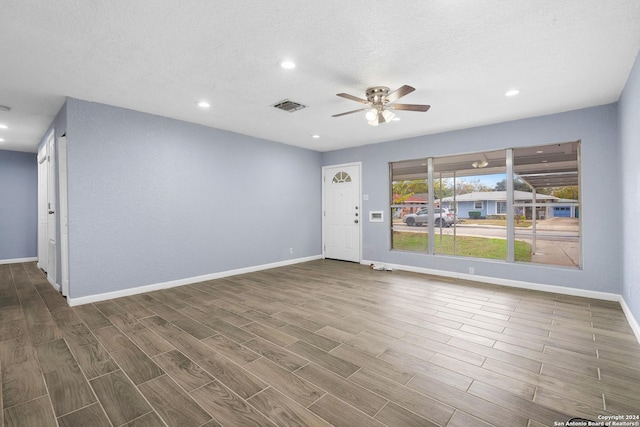 unfurnished room with a textured ceiling, ceiling fan, and dark wood-type flooring