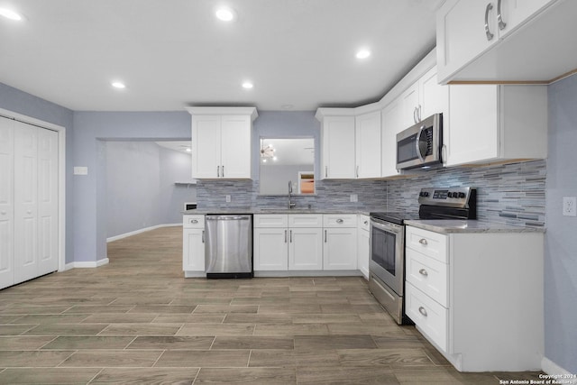 kitchen featuring light stone countertops, white cabinetry, sink, stainless steel appliances, and light hardwood / wood-style floors