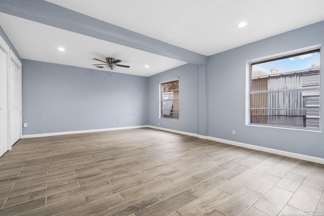 empty room with ceiling fan, plenty of natural light, and wood-type flooring