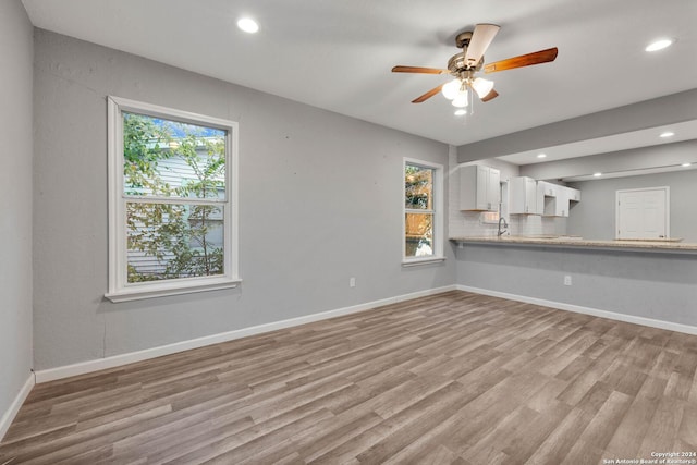 unfurnished living room with light hardwood / wood-style floors, ceiling fan, and sink