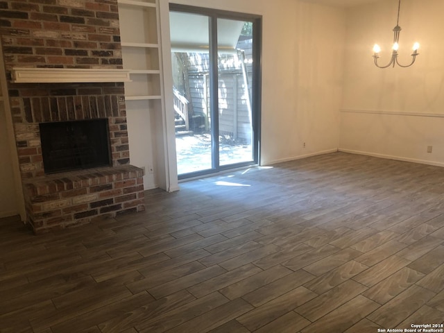 unfurnished living room featuring dark hardwood / wood-style floors, a fireplace, and a chandelier