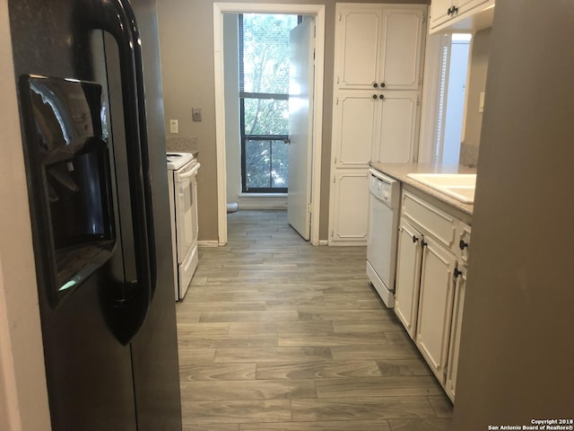 kitchen with white cabinetry, sink, light hardwood / wood-style floors, and white appliances