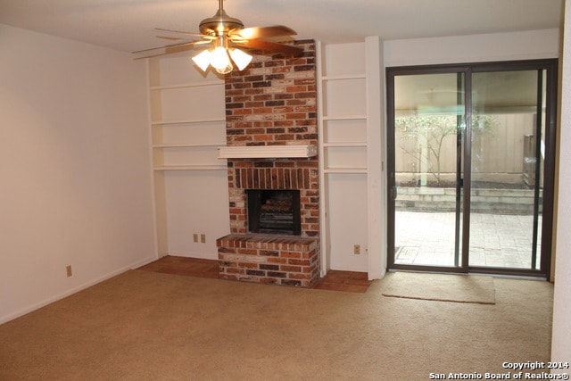 unfurnished living room with carpet flooring, a brick fireplace, and ceiling fan