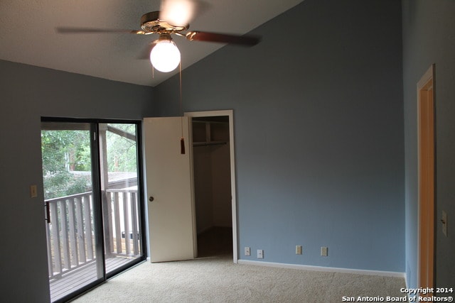 unfurnished bedroom with a walk in closet, lofted ceiling, access to outside, and a closet