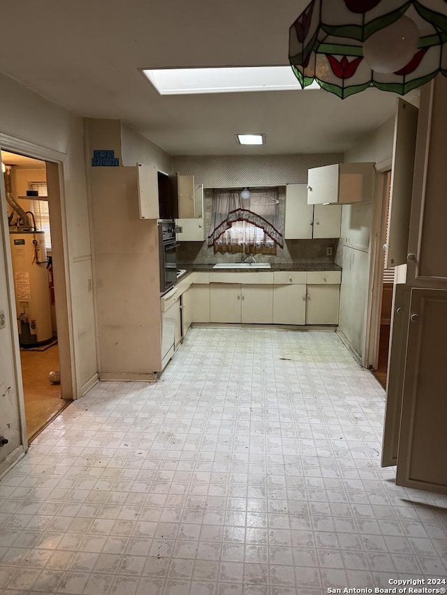 kitchen with cream cabinets, gas water heater, oven, and sink