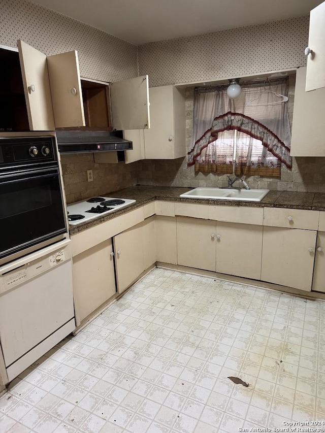 kitchen with cream cabinetry, white appliances, and sink