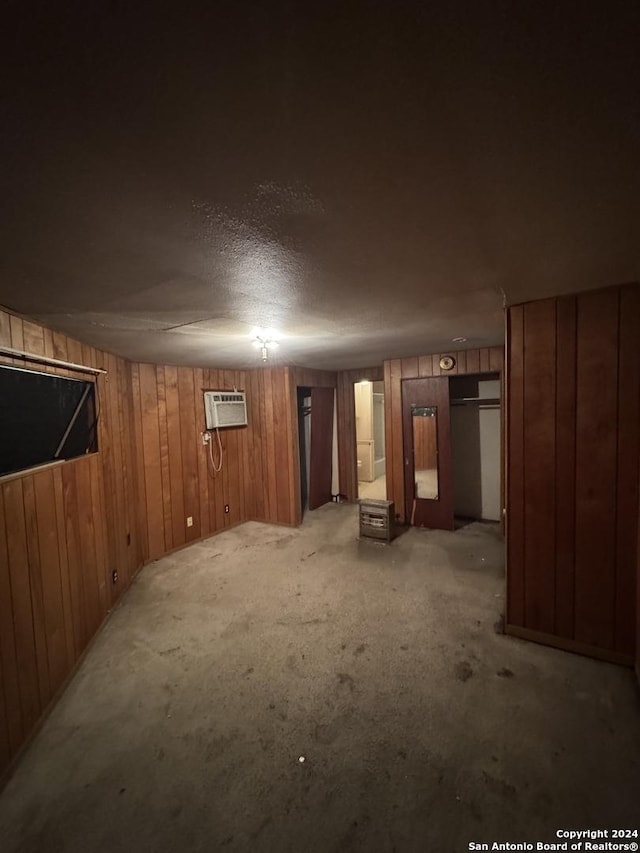 basement featuring wood walls, light colored carpet, and an AC wall unit