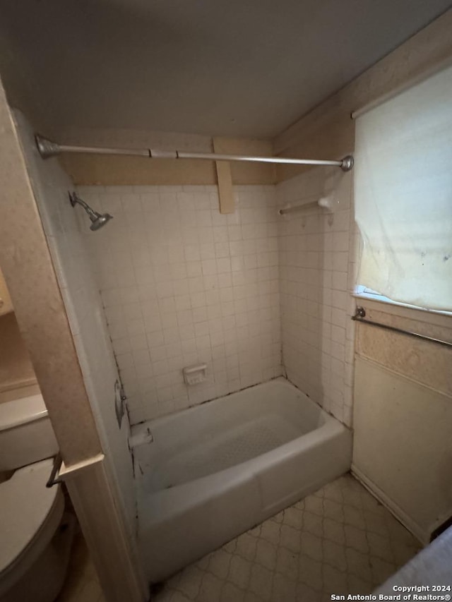 bathroom with tiled shower / bath combo and toilet