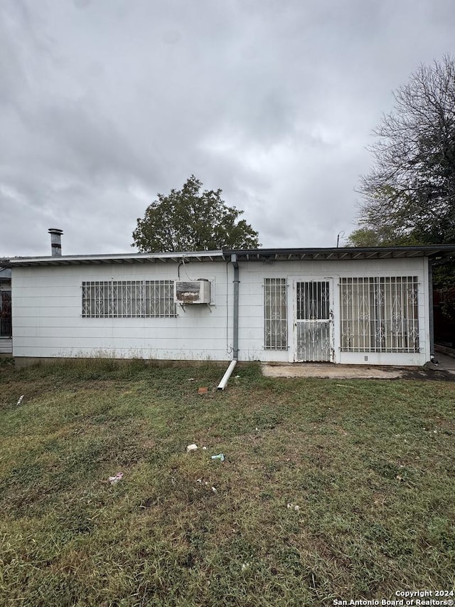 rear view of house featuring a yard and a wall unit AC