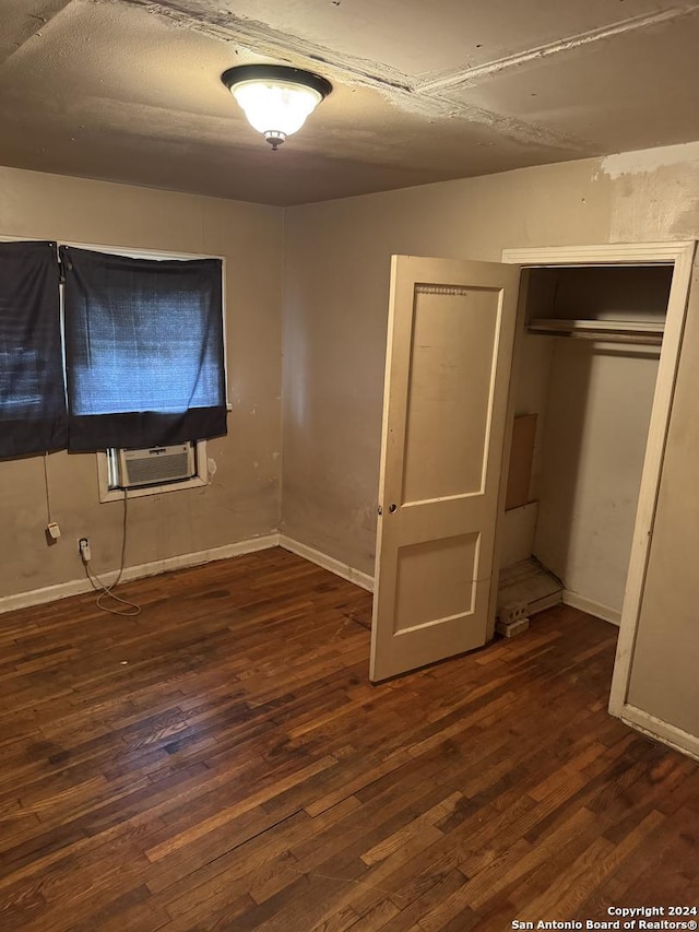 unfurnished bedroom with a closet, dark hardwood / wood-style flooring, and cooling unit