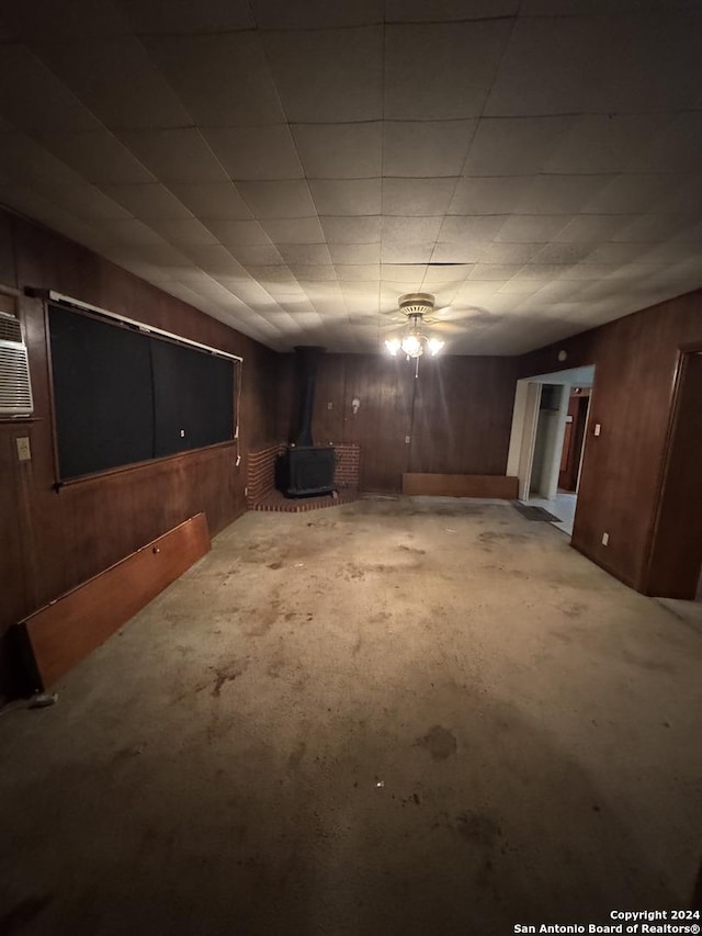 basement with a wood stove and wood walls