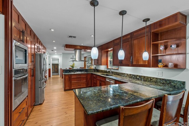 kitchen featuring kitchen peninsula, pendant lighting, a kitchen bar, and appliances with stainless steel finishes