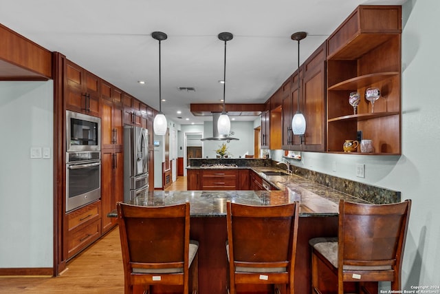 kitchen featuring kitchen peninsula, stainless steel appliances, decorative light fixtures, and light wood-type flooring