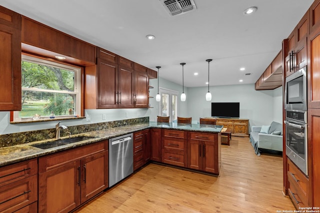 kitchen featuring sink, kitchen peninsula, pendant lighting, light hardwood / wood-style floors, and appliances with stainless steel finishes