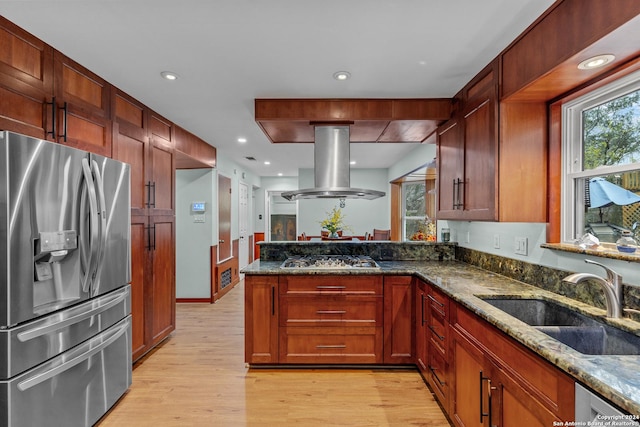 kitchen with sink, island exhaust hood, dark stone countertops, light hardwood / wood-style floors, and appliances with stainless steel finishes