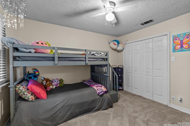 bedroom with ceiling fan with notable chandelier, light colored carpet, a textured ceiling, and a closet