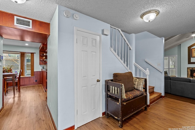 hallway featuring light hardwood / wood-style floors and a textured ceiling