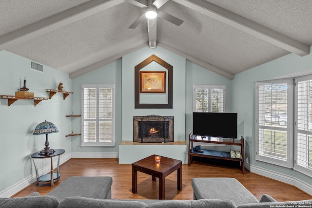 living room with lofted ceiling with beams, plenty of natural light, ceiling fan, and wood-type flooring