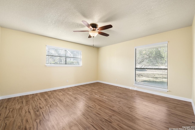 spare room with plenty of natural light, ceiling fan, wood-type flooring, and a textured ceiling