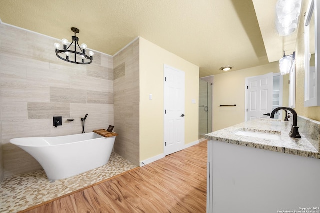 bathroom featuring vanity, wood-type flooring, tile walls, a notable chandelier, and shower with separate bathtub