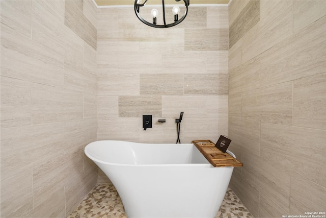 bathroom featuring a bath, tile walls, and an inviting chandelier