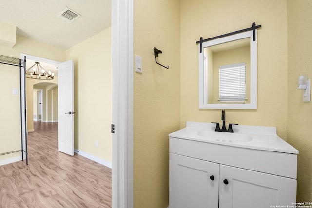 bathroom with vanity, an inviting chandelier, and hardwood / wood-style flooring