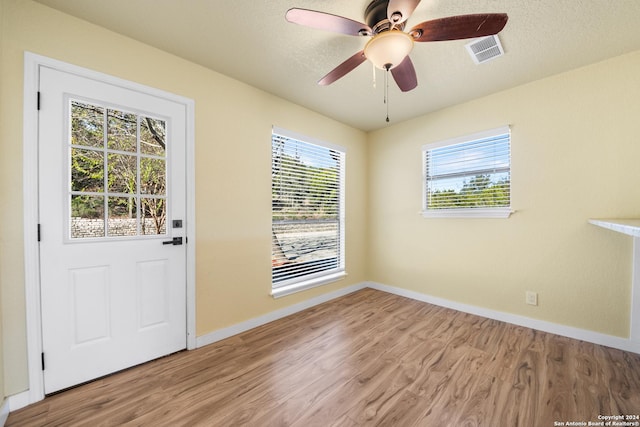 doorway to outside featuring a textured ceiling, light wood-type flooring, a wealth of natural light, and ceiling fan