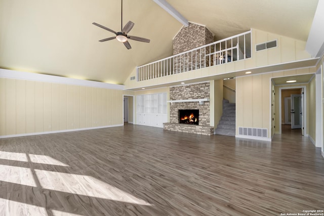 unfurnished living room with a brick fireplace, ceiling fan, wood-type flooring, high vaulted ceiling, and beamed ceiling