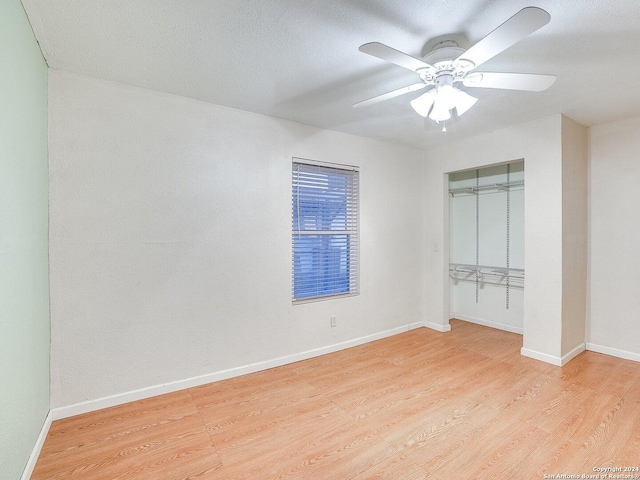 unfurnished bedroom featuring ceiling fan, a closet, and light wood-type flooring