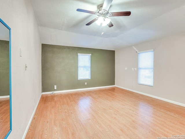 spare room featuring plenty of natural light, vaulted ceiling, and light hardwood / wood-style flooring