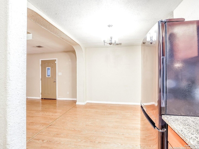 unfurnished dining area featuring light hardwood / wood-style flooring and a textured ceiling