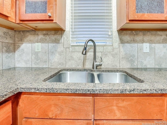 kitchen featuring light stone countertops, backsplash, and sink